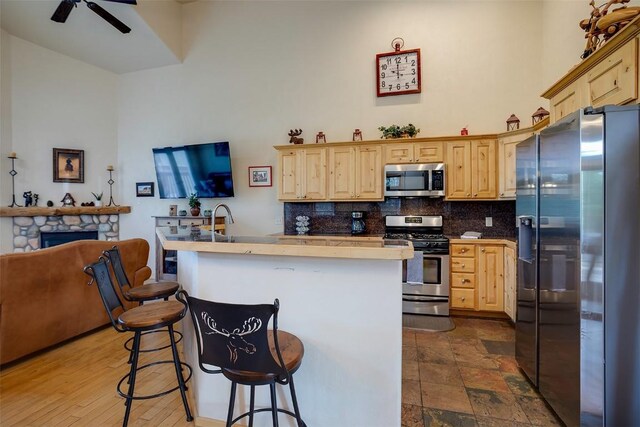 631 Parkview Dr, Steamboat Springs, CO 80487 - kitchen with appliances with stainless steel finishes, light brown cabinets, open floor plan, decorative backsplash, and a kitchen breakfast bar