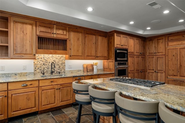 2600 Eagleridge Dr Unit 26, Steamboat Springs, CO 80487 - kitchen featuring a sink, appliances with stainless steel finishes, a tray ceiling, a kitchen breakfast bar, and brown cabinets