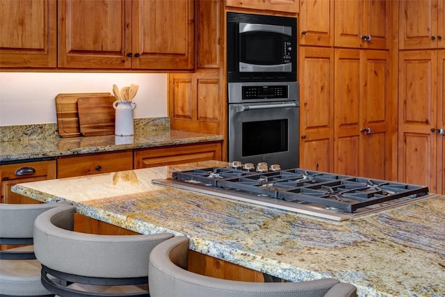 2600 Eagleridge Dr Unit 26, Steamboat Springs, CO 80487 - kitchen featuring stainless steel appliances, brown cabinets, light stone counters, and a breakfast bar