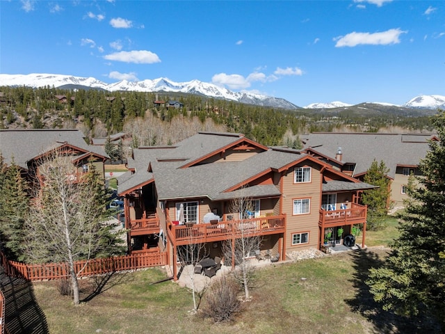 back of house featuring a deck with mountain view and a shingled roof