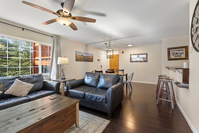 living area with ceiling fan, baseboards, and dark wood finished floors