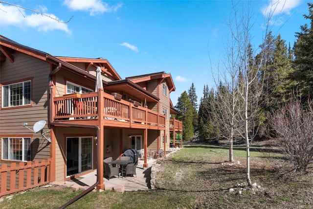rear view of property featuring a patio, a wooden deck, and a yard