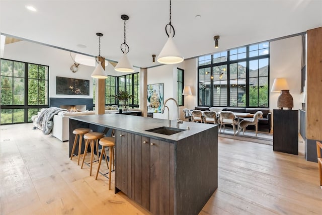 628 Independence Rd, Keystone, CO 80435 - kitchen featuring open floor plan, light wood-style floors, dark brown cabinets, decorative light fixtures, and a center island with sink