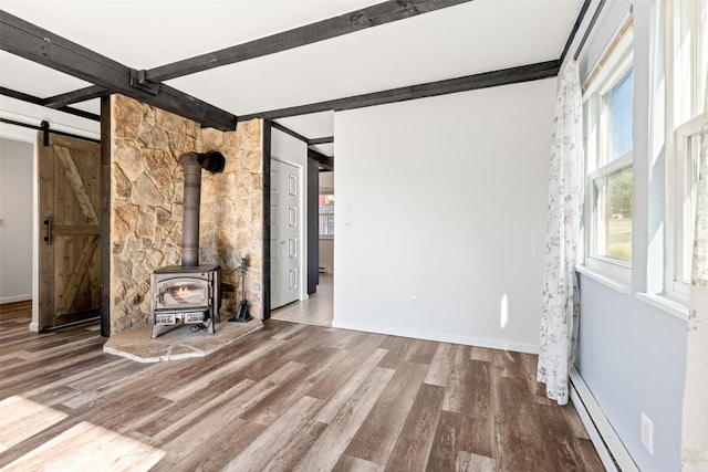 8011 Ryan Gulch Rd Unit B2, Silverthorne, CO 80498 - unfurnished living room featuring beamed ceiling, wood finished floors, baseboard heating, a wood stove, and a barn door