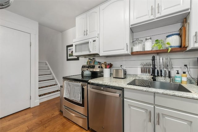 4 Sequoia Ct, Steamboat Springs, CO 80487 - kitchen featuring appliances with stainless steel finishes, light wood-style floors, white cabinets, and light stone countertops