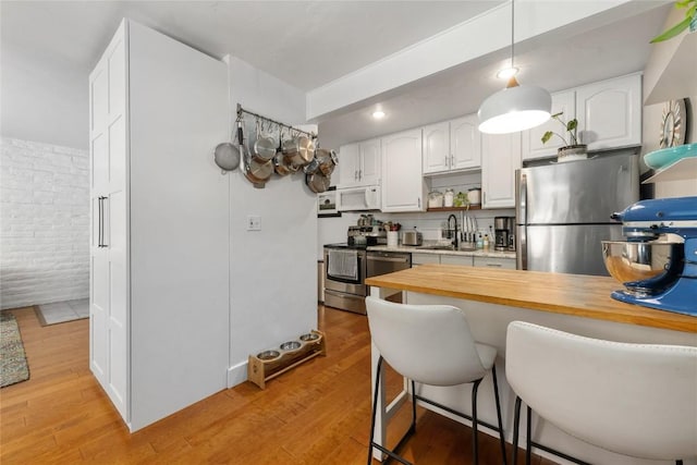 4 Sequoia Ct, Steamboat Springs, CO 80487 - kitchen featuring stainless steel appliances, a kitchen bar, white cabinets, and light wood finished floors