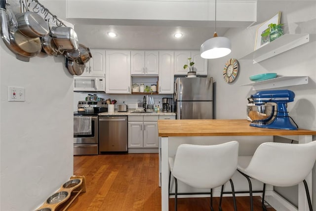 4 Sequoia Ct, Steamboat Springs, CO 80487 - kitchen with open shelves, stainless steel appliances, a kitchen breakfast bar, wood finished floors, and recessed lighting
