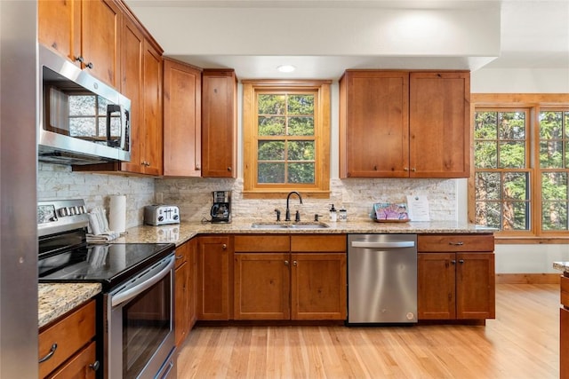 50 Cooney Ct, Blue River, CO 80424 - kitchen featuring stainless steel appliances, light wood-style floors, brown cabinetry, backsplash, and light stone countertops