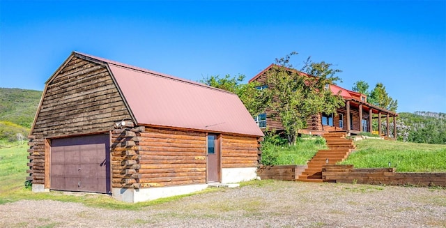 30955 Whitecotton Ct, Steamboat Springs, CO 80487 - view of front of property featuring log exterior, a detached garage, a gambrel roof, an outbuilding, and metal roof