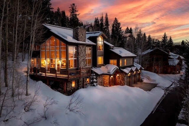 1064 Steamboat Blvd, Steamboat Springs, CO 80487 - snow covered property featuring an attached garage, a chimney, and stone siding