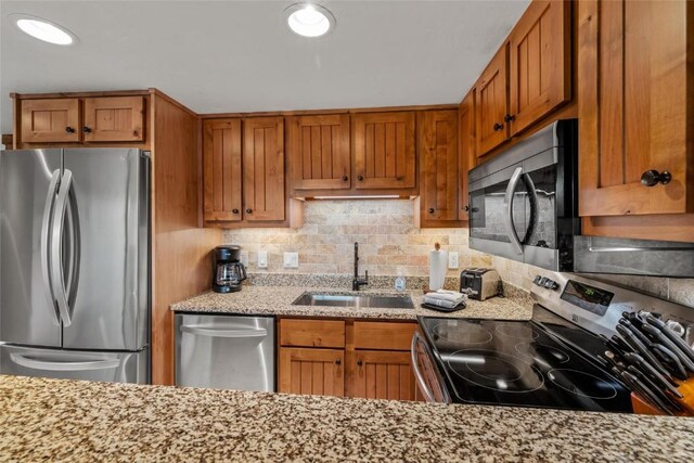 2275 Storm Meadows Dr Unit 63, Steamboat Springs, CO 80487 - kitchen with stainless steel appliances, a sink, brown cabinetry, and tasteful backsplash