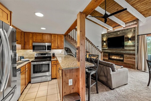 2275 Storm Meadows Dr Unit 63, Steamboat Springs, CO 80487 - kitchen with appliances with stainless steel finishes, open floor plan, light stone counters, brown cabinetry, and ceiling fan