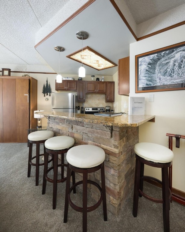 45 Beeler Pl Unit 301, Copper Mountain, CO 80443 - kitchen with appliances with stainless steel finishes, light carpet, a textured ceiling, hanging light fixtures, and a breakfast bar area