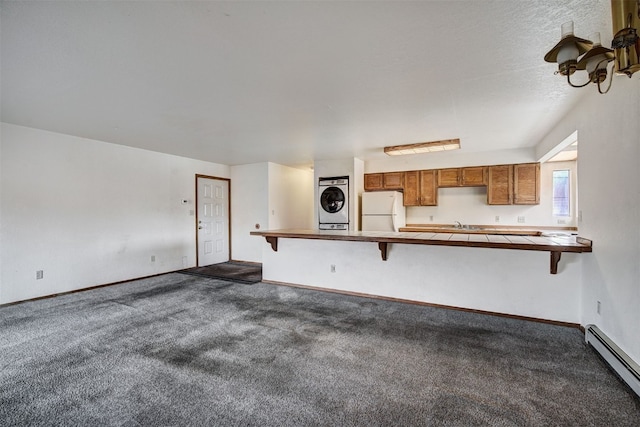 716 Lagoon Dr Unit D, Frisco, CO 80443 - unfurnished living room with a baseboard heating unit, baseboards, dark carpet, and stacked washer / drying machine