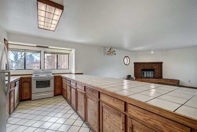 716 Lagoon Dr Unit D, Frisco, CO 80443 - kitchen featuring white range with electric cooktop, stainless steel dishwasher, tile countertops, brown cabinets, and light tile patterned flooring