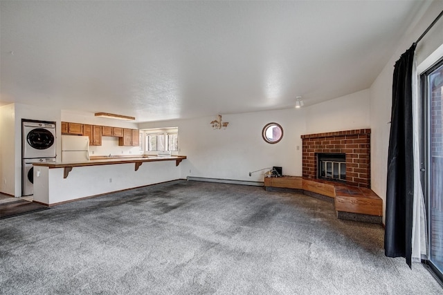 716 Lagoon Dr Unit D, Frisco, CO 80443 - unfurnished living room featuring a baseboard heating unit, stacked washer and dryer, light carpet, and a fireplace
