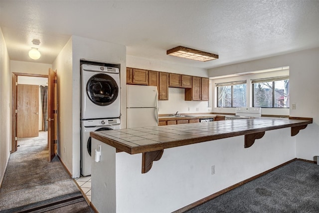 716 Lagoon Dr Unit D, Frisco, CO 80443 - kitchen with a sink, stacked washing maching and dryer, a breakfast bar, white appliances, and a peninsula