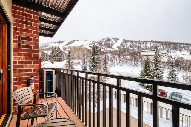 snow covered back of property featuring a mountain view