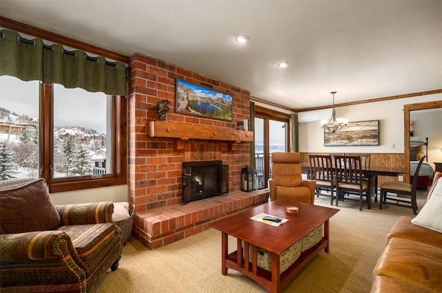 living room with crown molding, an inviting chandelier, light carpet, wooden walls, and a fireplace