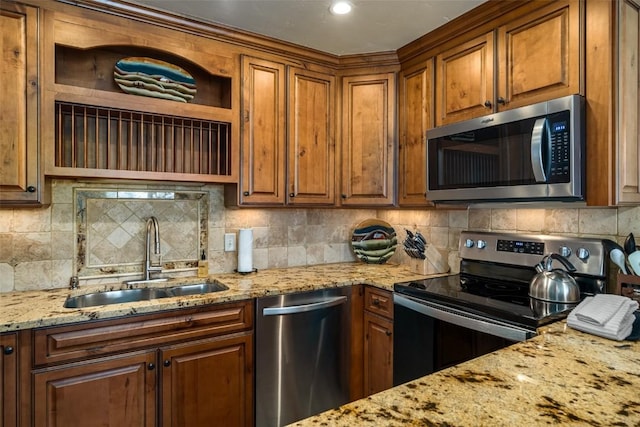 kitchen with light stone counters, appliances with stainless steel finishes, sink, and decorative backsplash