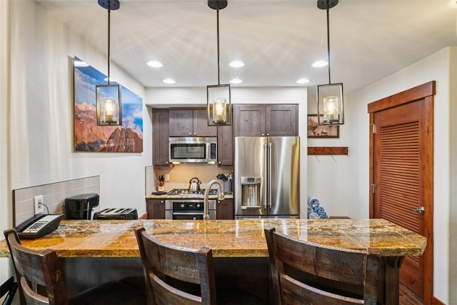 1521 Ski Hill Rd Unit 8312, Breckenridge, CO 80424 - kitchen featuring stainless steel appliances, a peninsula, dark brown cabinets, a breakfast bar, and pendant lighting