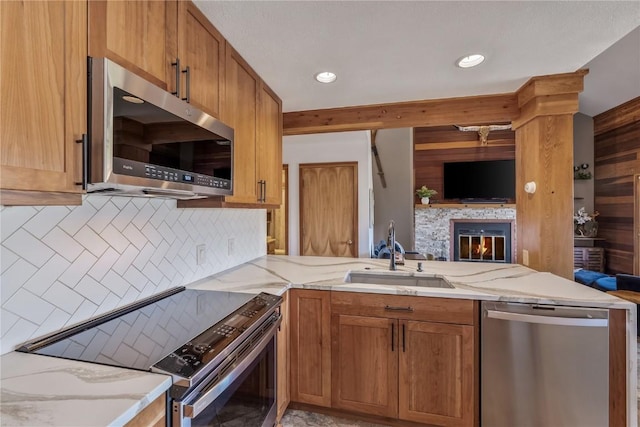 91200 Ryan Gulch Rd Unit 91222, Silverthorne, CO 80498 - kitchen featuring appliances with stainless steel finishes, a sink, open floor plan, light stone counters, and a glass covered fireplace