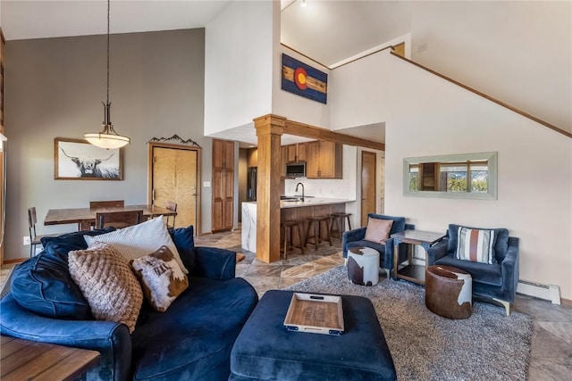 91200 Ryan Gulch Rd Unit 91222, Silverthorne, CO 80498 - living room featuring high vaulted ceiling, decorative columns, a baseboard radiator, and baseboards