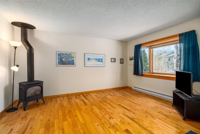 3 Cypress Ct Unit 3, Steamboat Springs, CO 80487 - unfurnished living room featuring a wood stove, light wood-style floors, baseboards, a textured ceiling, and a baseboard radiator