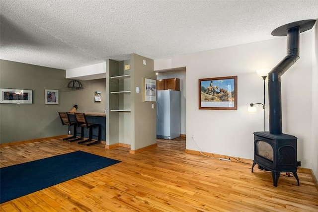 3 Cypress Ct Unit 3, Steamboat Springs, CO 80487 - unfurnished living room featuring baseboards, a textured ceiling, light wood-style flooring, and a wood stove