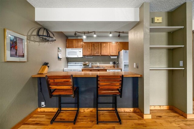 3 Cypress Ct Unit 3, Steamboat Springs, CO 80487 - kitchen featuring brown cabinets, light wood-style floors, white appliances, a peninsula, and butcher block counters