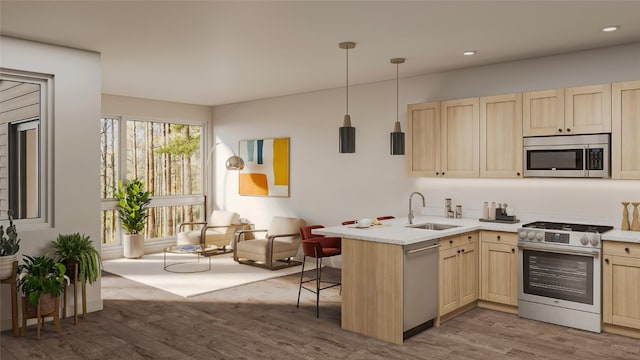 kitchen with kitchen peninsula, appliances with stainless steel finishes, a kitchen bar, sink, and decorative light fixtures