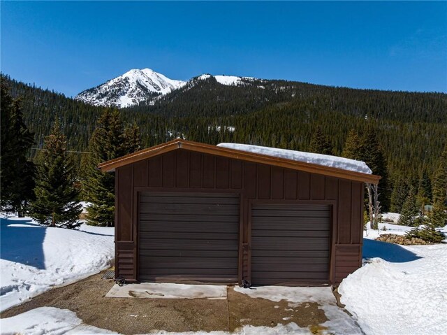 5277 Montezuma Rd, Montezuma, CO 80435 - snow covered garage featuring a detached garage, a view of trees, and a mountain view