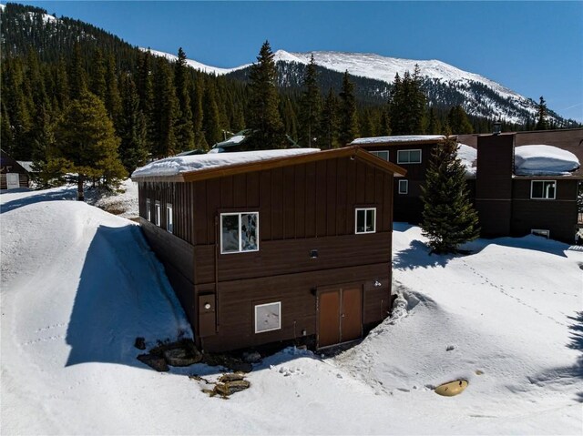 5277 Montezuma Rd, Montezuma, CO 80435 - view of snowy exterior with a wooded view, a mountain view, and board and batten siding