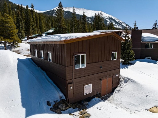 5277 Montezuma Rd, Montezuma, CO 80435 - view of snowy exterior with a mountain view, a view of trees, and board and batten siding