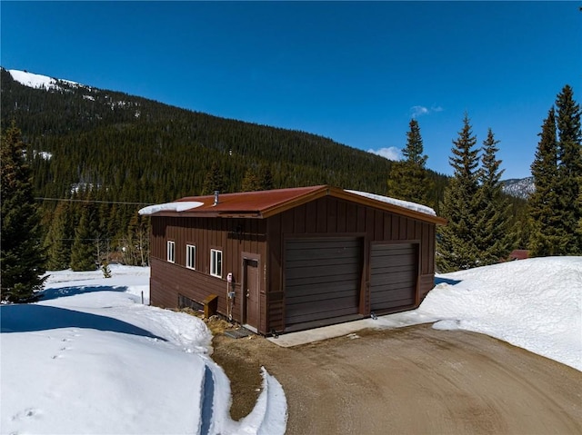 5277 Montezuma Rd, Montezuma, CO 80435 - snow covered garage featuring a view of trees, a mountain view, and a garage