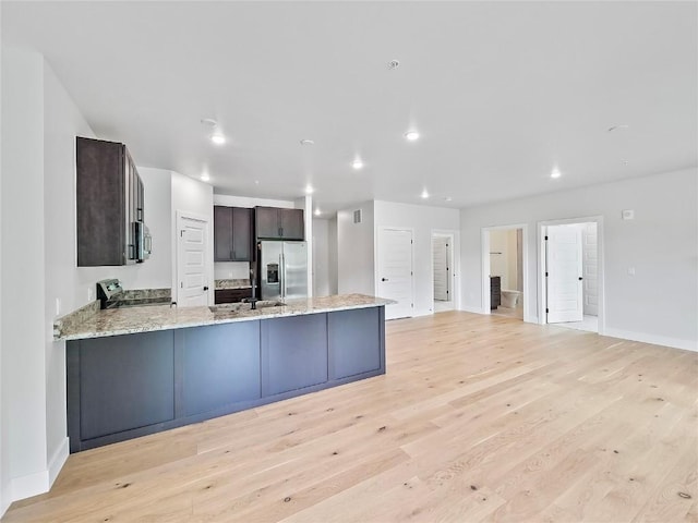 kitchen with stainless steel appliances, a peninsula, baseboards, light wood-type flooring, and dark brown cabinetry