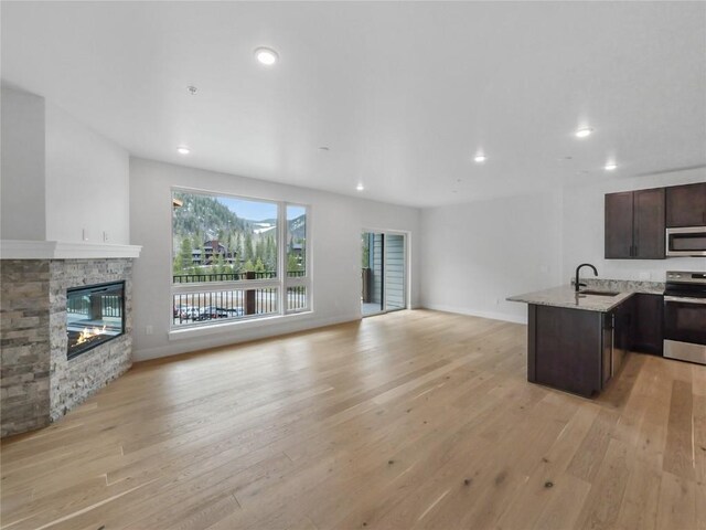 kitchen featuring stainless steel appliances, open floor plan, dark brown cabinets, light wood-style flooring, and recessed lighting