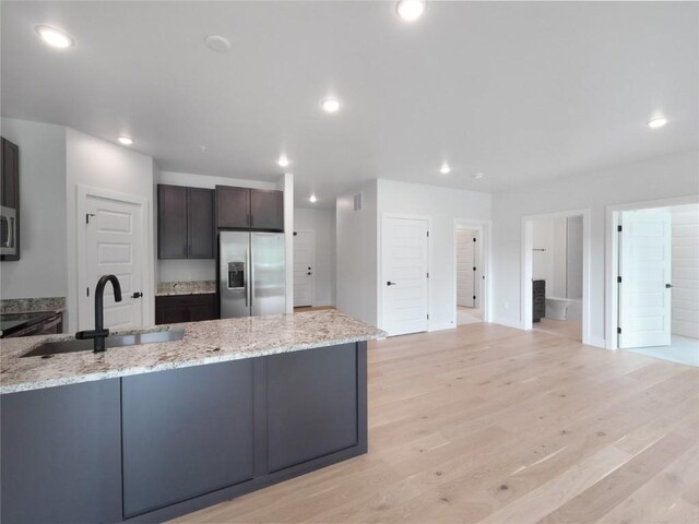 kitchen with stainless steel appliances, a sink, light stone countertops, recessed lighting, and light wood-style flooring