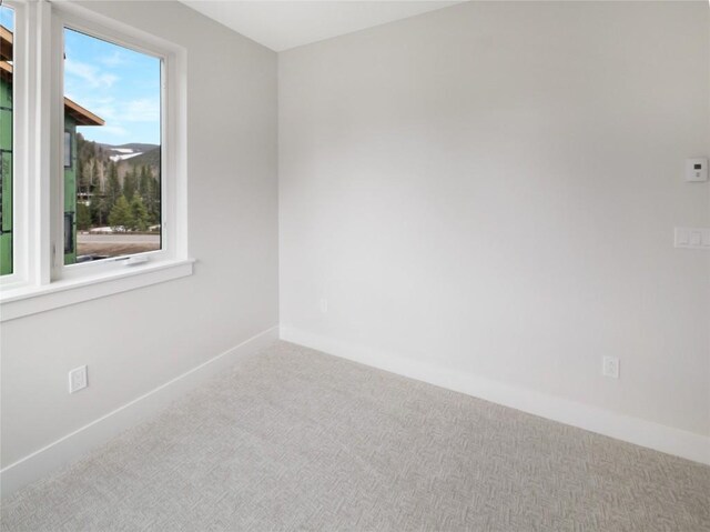 spare room featuring carpet and baseboards