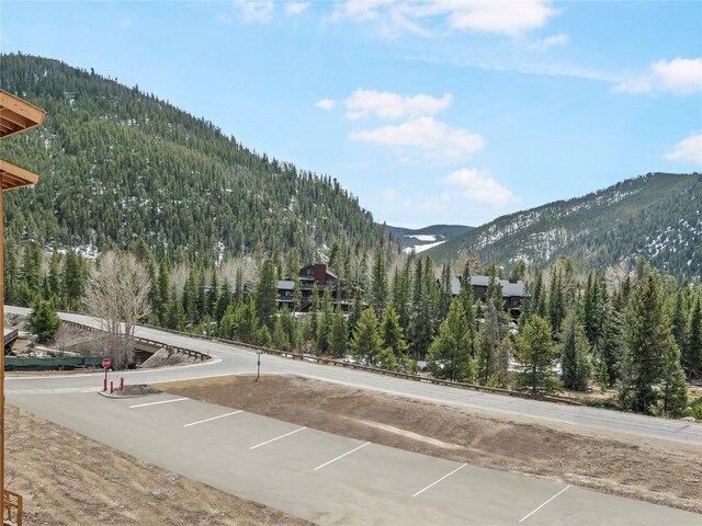 view of road featuring a mountain view, a forest view, and traffic signs