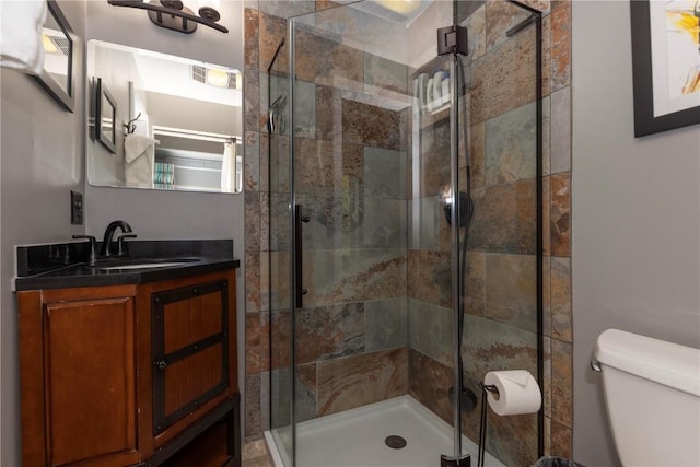 bathroom featuring toilet, vanity, visible vents, and a stall shower