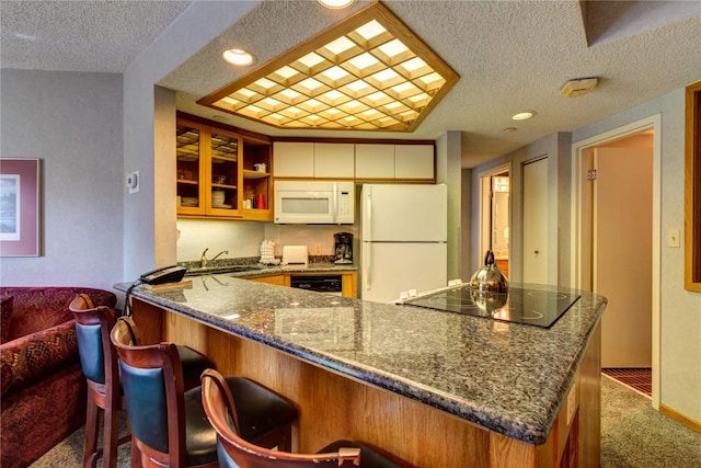 kitchen with carpet floors, dark stone countertops, a textured ceiling, and white appliances