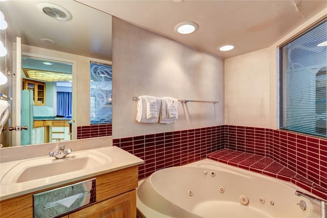 full bath with vanity and a tub with jets