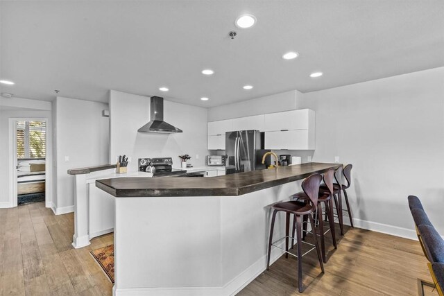 1724 Ski Time Square Dr Unit R6, Steamboat Springs, CO 80487 - kitchen featuring wall chimney range hood, stainless steel appliances, baseboards, dark countertops, and recessed lighting