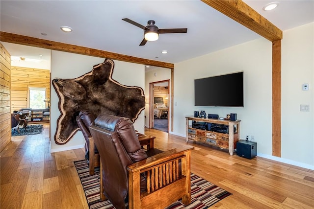 living area featuring light wood-style flooring, beam ceiling, recessed lighting, a ceiling fan, and wood walls
