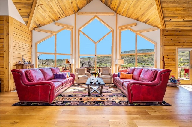 living area with a mountain view, wood walls, high vaulted ceiling, and wooden ceiling
