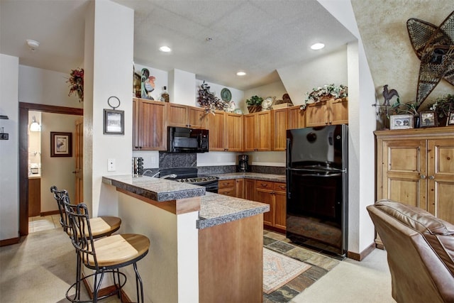 kitchen with a breakfast bar, a peninsula, light colored carpet, and black appliances