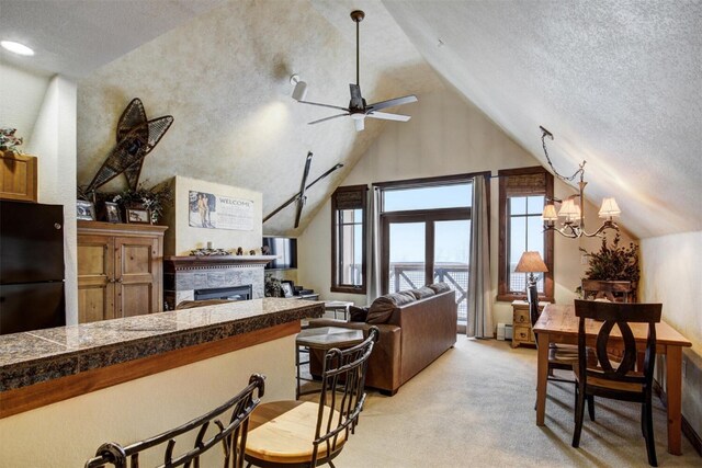 kitchen with a ceiling fan, tile counters, a textured ceiling, a glass covered fireplace, and light colored carpet
