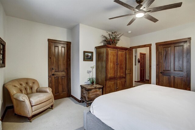bedroom with light colored carpet, ceiling fan, and baseboards