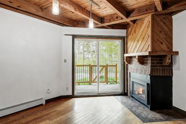 8500 Ryan Gulch Rd Unit G2, Wildernest, CO 80498 - unfurnished living room featuring baseboard heating, wood ceiling with exposed beams, hardwood / wood-style flooring, a brick fireplace, and baseboards